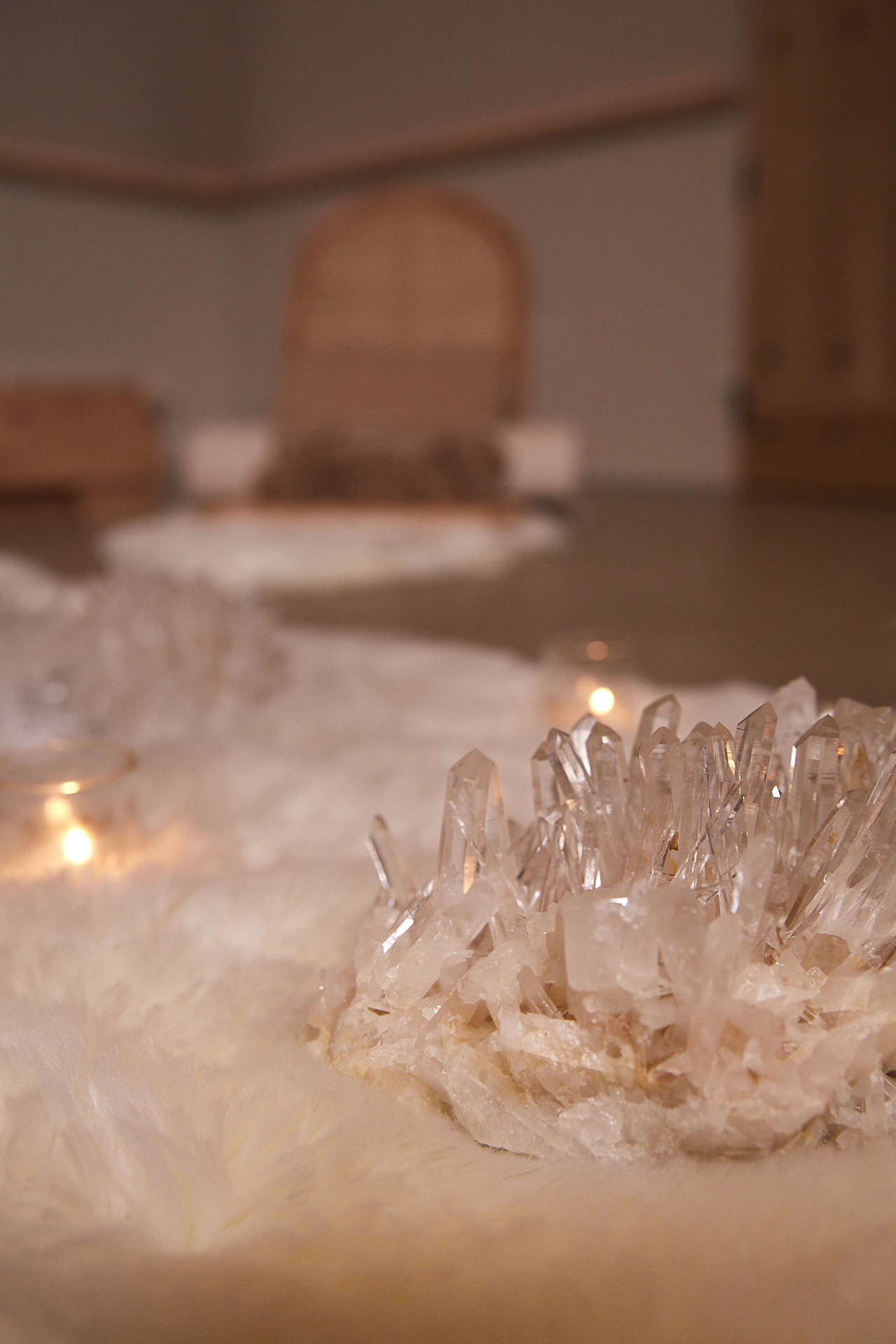 Clear quartz crystal cluster on a white fur rug with the Meditation Dome in the background