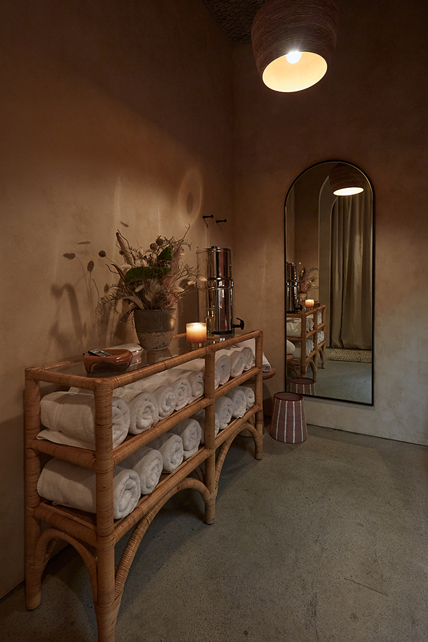 Rattan towel rack with rolled white towels and water dispenser in the vestibule