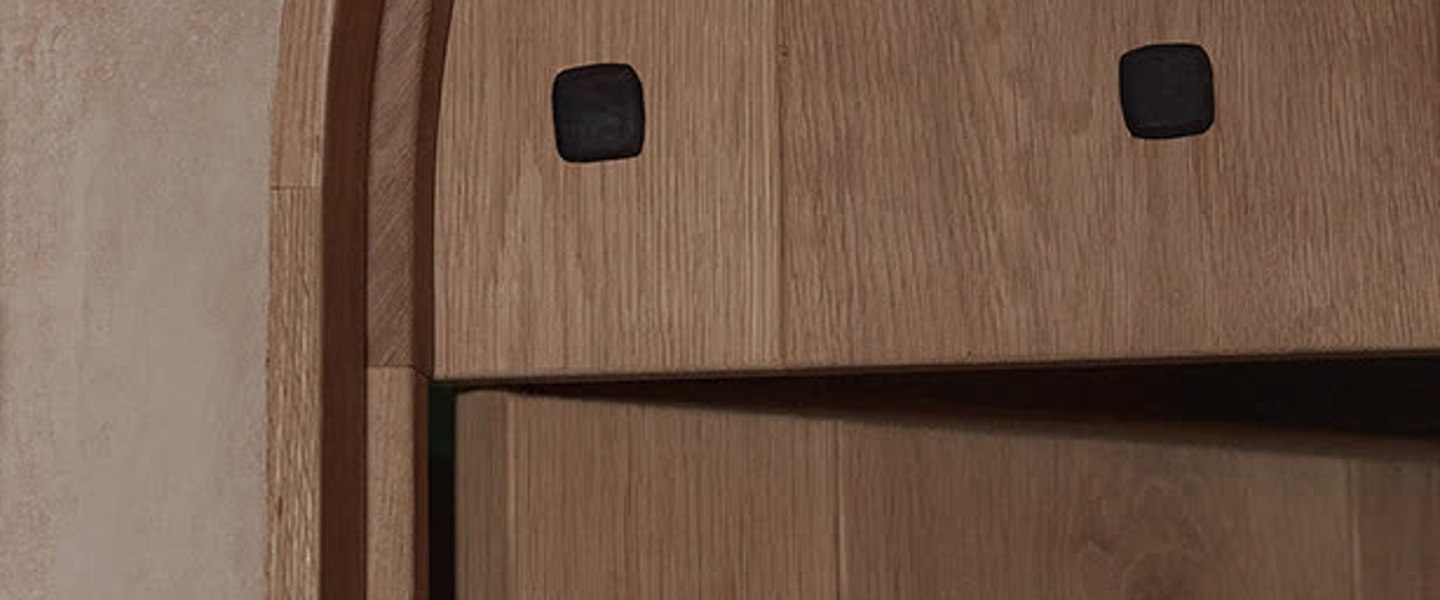 PALOMA's arched front door in pale oak, closed, with the handle catching afternoon light.