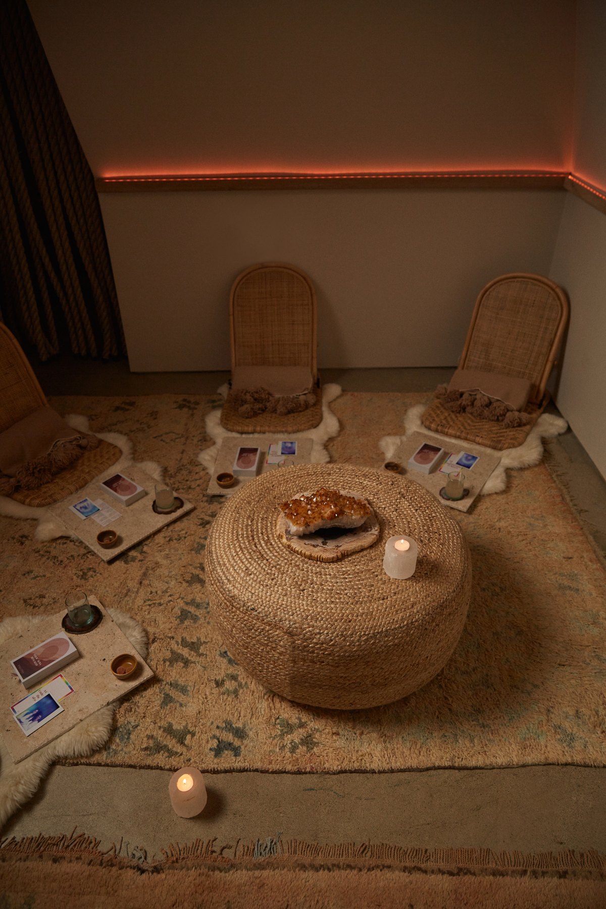 The Dome set for a circle — rattan chairs on sheepskins, a citrine cluster on a woven pouf, candles lit.