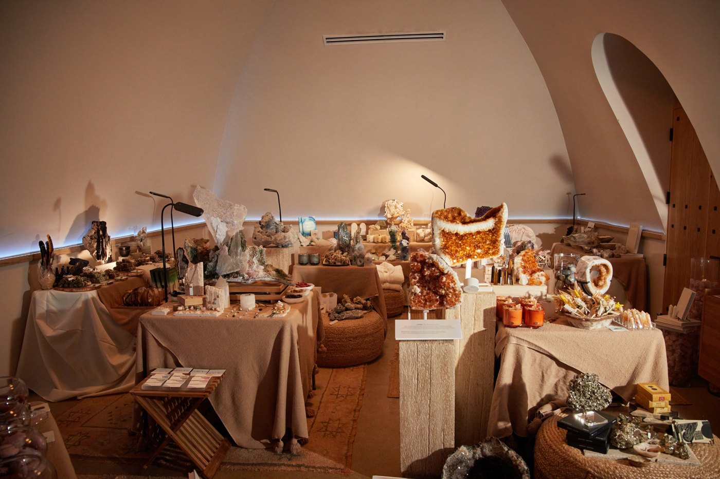 The Edit laid out as a market in the Dome — draped tables, crystals and products under warm light.